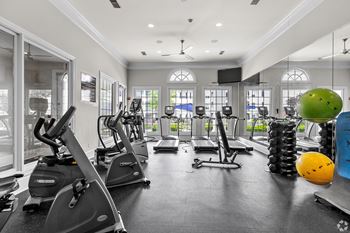A gym with treadmills, elliptical machines, and exercise balls.